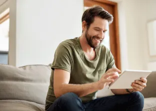 Un homme dans un canapé regarde une tablette